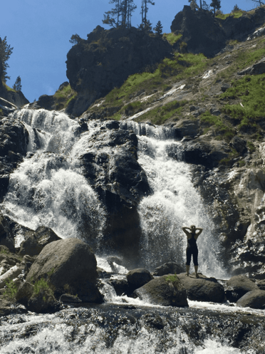 Girl facing a waterfall after a hike.