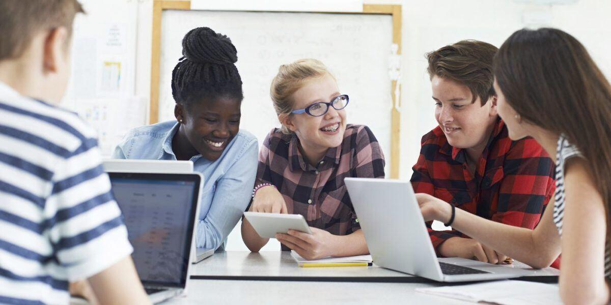 Group Of Teenage Students Collaborating On Project In IT Class